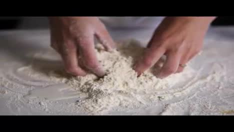 Close-Up-view-of-female-hands-mixing-flour-with-eggs-and-milk-on-the-kitchen-surface.-Slow-motion-shot
