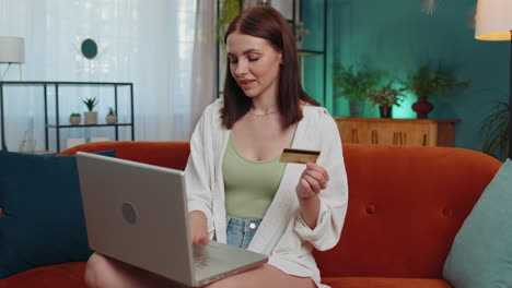 Young-woman-using-credit-bank-card-and-laptop,-transferring-money,-purchases-online-shopping