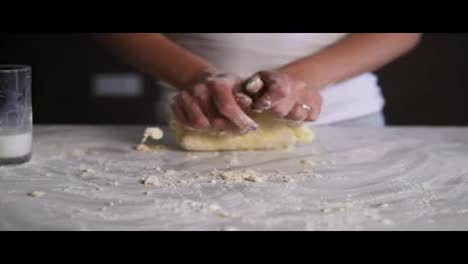 Woman-kneading-dough-in-flour-on-the-table.-Baker-prepares-the-dough.-Hands-kneading-dough.-Slow-motion-shot
