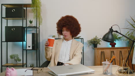 Businesswoman-enters-office-start-working-on-laptop-computer-at-desk-and-drinking-morning-coffee