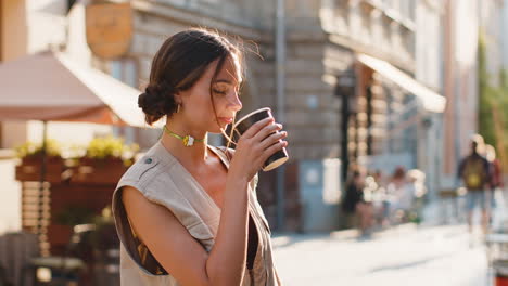 Young-woman-girl-enjoying-drinking-morning-coffee-hot-drink,-relaxing,-taking-a-break-in-city-street