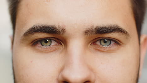 Extreme-close-up-macro-portrait-of-young-face,-bearded-man's-eyes-looking-at-camera,-smiling