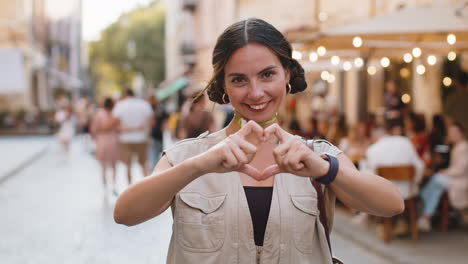 Young-woman-makes-symbol-of-love,-showing-heart-sign-to-camera,-express-romantic-positive-feelings