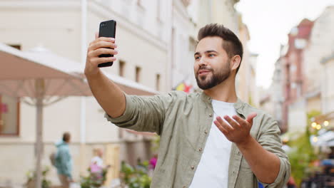 Junger-Blogger,-Der-Ein-Selfie-Per-Smartphone-Videoanruf-Online-Mit-Abonnenten-In-Der-Stadtstraße-Macht