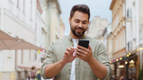 Bearded-man-use-mobile-smartphone-celebrating-win-good-message-news-outdoors-in-urban-city-street