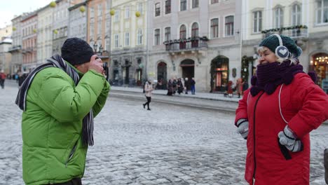Senior-couple-tourists-grandmother-grandfather-taking-photo-pictures-on-retro-camera-in-winter-city