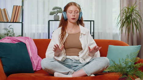 Teenager-red-hair-girl-breathes-deeply-with-mudra-gesture,-eyes-closed,-meditating,-listening-music