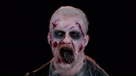 Frightening-scary-man-with-Halloween-zombie-bloody-wounded-makeup,-showing-tongue,-trying-to-scare