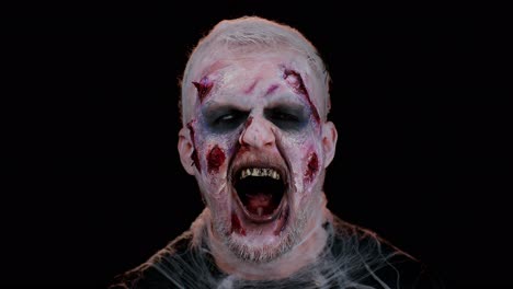 Unheimlicher-Mann-Halloween-Verrückter-Zombie-Mit-Blutigen-Verwundeten-Narben-Im-Gesicht,-Der-Versucht,-Im-Schwarzen-Raum-Angst-Zu-Machen