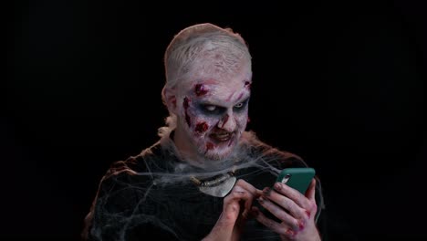 Happy-excited-sinister-man-Halloween-zombie-use-smartphone-celebrating-lottery-win,-success-luck