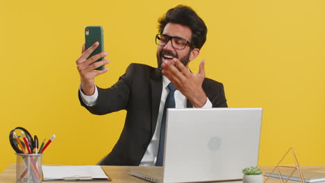 Indian-businessman-making-phone-call-online-conversation,-mobile-loudspeaker-talking,-waving-hello