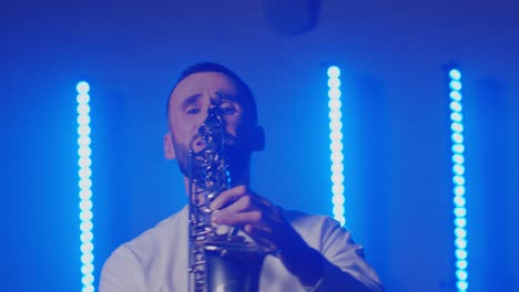 Live-performance-of-saxophonist-man-with-saxophone,-dancing-on-concert-musician-stage-with-lights