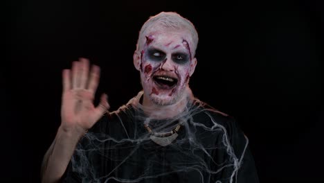 Creepy-Halloween-zombie-man-smiling-friendly-waving-hands-gesturing-hello-or-goodbye,-welcoming
