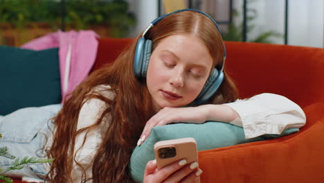 Fröhliches-Teenager-Mädchen-Mit-Drahtlosen-Kopfhörern-Entspannt-Sich-Zu-Hause-Auf-Dem-Sofa-Und-Hört-Lieblingsmusik