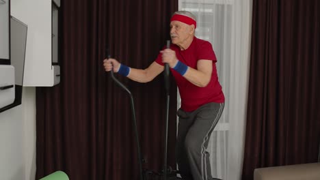 Healthy-elderly-senior-grandfather-model-exercising-sport-workout-on-orbitrek-in-room-at-home