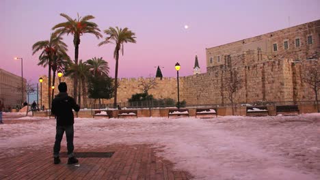 Ein-Mann-Steht-In-Der-Abenddämmerung-Auf-Einem-Platz-In-Jerusalem-Nach-Einem-Seltenen-Schneefall