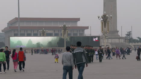 Chinese-troops-march-through-Tiananmen-Square-with-large-electronic-billboard-background