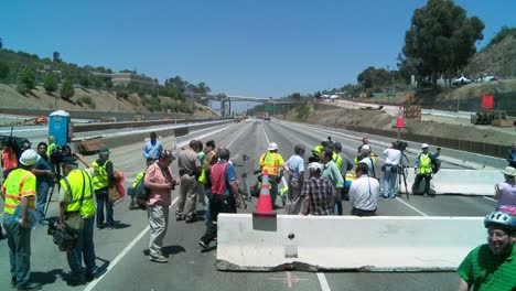 Zoom-out-from-crews-working-on-a-closed-of-the-405-freeway-in-Los-Angles-to-show-a-crowd-of-onlookers