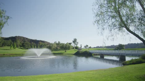 Pan-left-wide-view-of-a-golf-course-with-a-fountain-lake-and-bridge