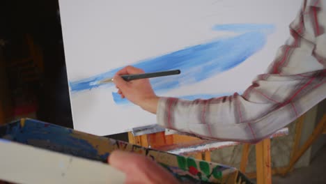 An-artist-spreads-blue-paint-on-a-canvas