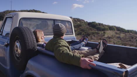 A-couple-sits-in-the-back-of-a-pickup-truck-parked-on-a-rural-road