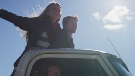 A-couple-stands-in-the-bed-of-a-pickup-truck-as-it-drives-along-a-rural-road-2
