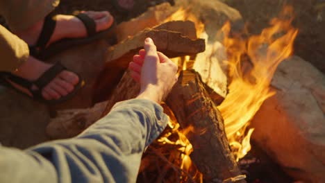 Closeup-of-feet-and-hands-near-a-campfire