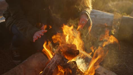 Closeup-of-a-couple-warming-their-hands-over-a-campfire