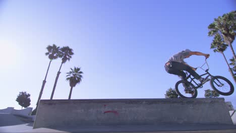 Low-angle-view-of-a-BMX-bike-rider-doing-a-wheelie-at-a-skatepark