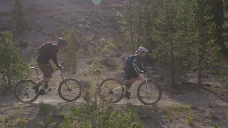 Two-mountain-bikers-ride-through-a-forest-1