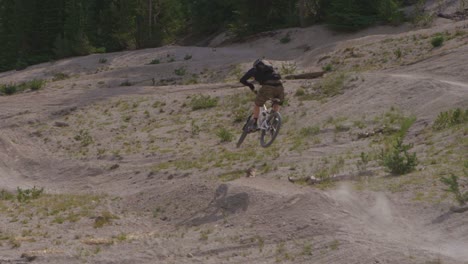 A-mountain-biker-does-a-jump-on-a-path-near-a-forest