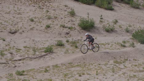 A-mountain-biker-rides-on-a-dirt-path-near-a-forest