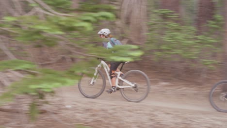 Two-mountain-bikers-race-on-a-path-through-a-forest