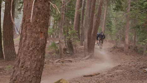 Two-mountain-bikers-race-on-a-path-through-a-forest-1