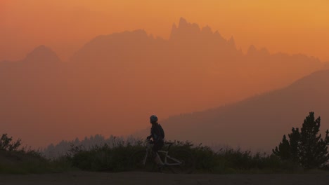 A-mountain-biker-pulls-to-a-stop-on-a-hillside-at-sunset-and-takes-a-picture