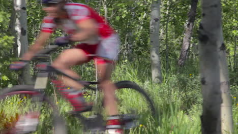 A-man-rides-a-mountain-bike-fast-through-a-dense-forest-3