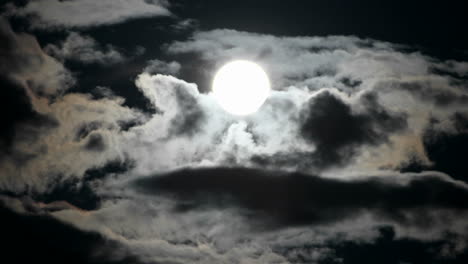 Una-Luna-Llena-Brillante-Se-Eleva-Mientras-Las-Nubes-Se-Mueven-Rápidamente-En-Un-Cielo-Nocturno