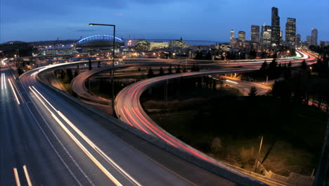 As-the-goldenhour-darkens-into-night-accelerated-traffic-on-the-Seattle-freeway-blurs-into-streaks-of-light-before-an-illuminated-city-skyline