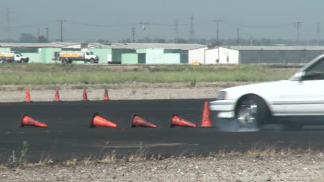 A-White-Car-Squeals-Its-Tires-And-Spins-Out-As-It-Is-Guided-Through-A-Drifting-Course-In-At-Camarillo-Airport-In-Camarillo-California