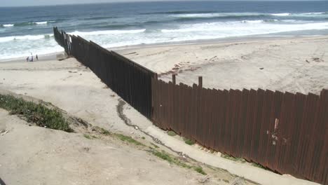 A-Family-Is-Seen-Playing-On-The-Beach-Next-To-The-Border-Wall-In-Tijuana