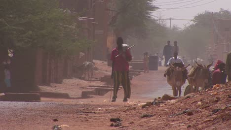 People-walk-down-a-road-through-the-Sahara-desert-in-Mali-during-a-windstorm