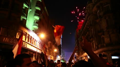 Los-Manifestantes-Ondean-Banderas-Y-Se-Disparan-Fuegos-Artificiales-En-Un-Mitin-Nocturno-En-El-Cairo,-Egipto