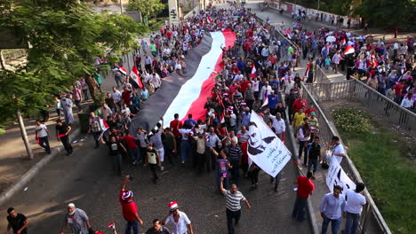 Protestors-march-and-carry-a-large-flag-in-Cairo-Egypt