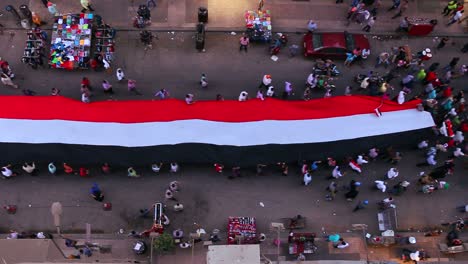 Vista-Desde-Arriba-Mirando-Hacia-Abajo-Mientras-Los-Manifestantes-Portando-Pancartas-Marchan-En-Las-Calles-De-El-Cairo,-Egipto-2