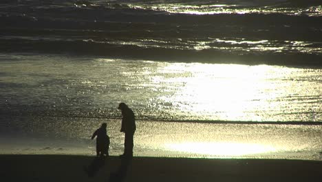A-Man-And-A-Two-Children-Explore-The-Beach-As-The-Tide-Goes-Out-During-The-Goldenhour