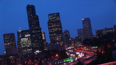 Ein-Schräger-Blick-Auf-Die-Skyline-Der-Innenstadt-Von-Seattle-Bei-Nacht-Mit-Verkehr