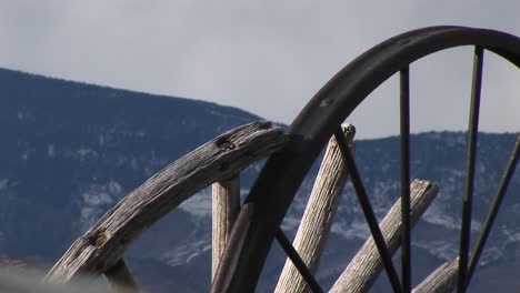 Camera-Looks-At-Mountains-Through-The-Broken-Spokes-Of-Abandoned-Wagon-Wheels