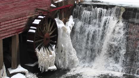 A-Closeup-Of-Water-Flowing-Past-A-Gristmill-Whose-Waterwheel-Is-Immobilized-By-Freezing-Temperatures