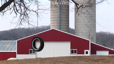 A-Montage-That-Includes-A-Tire-Swinging-From-A-Tree'S-Bare-Branches-A-Red-Barn-And-Twin-Silos