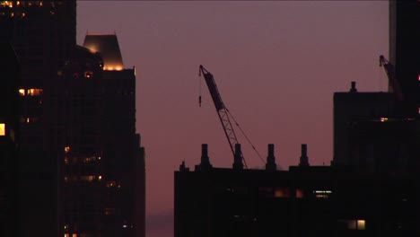 A-Building-Crane-Rests-On-A-Rooftop-In-A-Goldenhour-Skyline-Shot